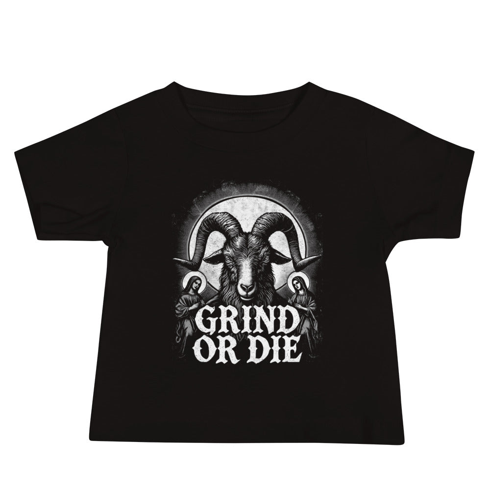 A toddler in a Bougie Boiz Club Grind Or Die baby t-shirt, featuring a white rams head graphic, stands against a plain white background. With short blonde hair and blue jeans, this determined little lifter already exudes style.