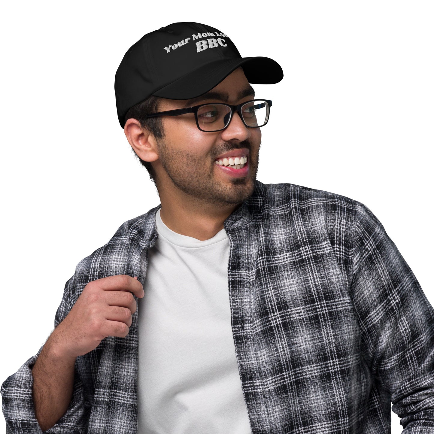 A person wearing a Bougie Boiz Clubs Your Mom Loves BBC embroidered hat, hands resting on the cap. Dressed in a black and white plaid shirt, they are viewed from behind against a simple background.