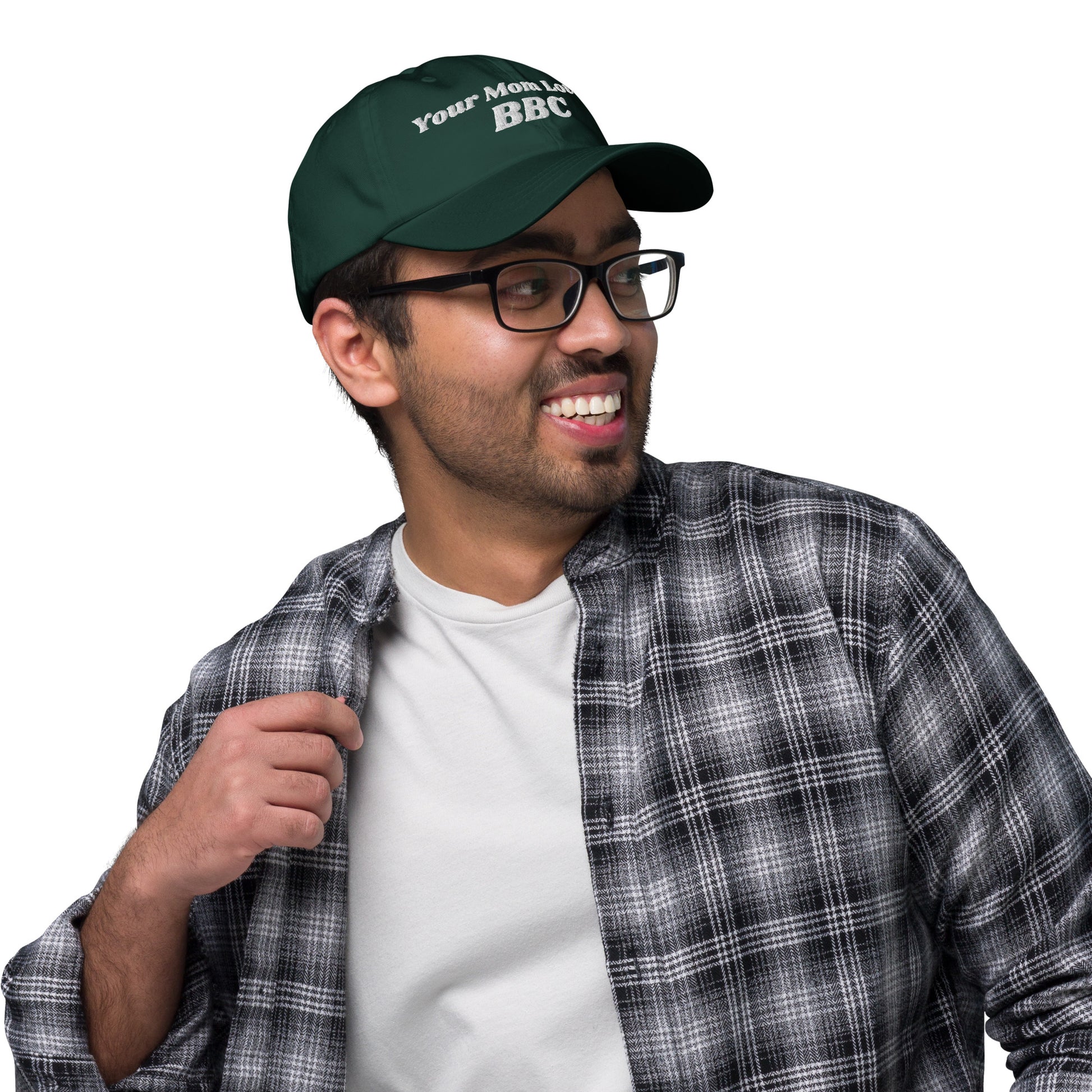 A person wearing a Bougie Boiz Clubs Your Mom Loves BBC embroidered hat, hands resting on the cap. Dressed in a black and white plaid shirt, they are viewed from behind against a simple background.