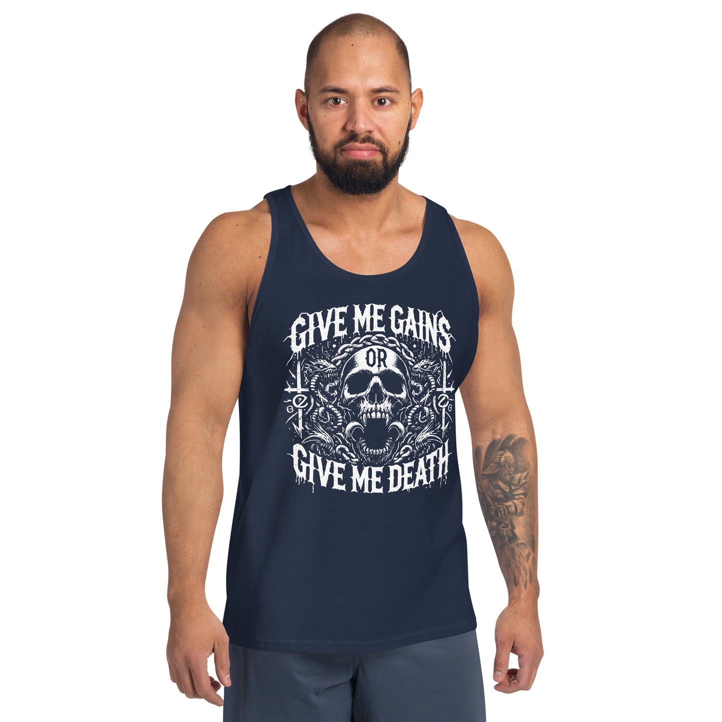 A bearded man embraces the iron life in a Bougie Boiz Club Give Me Gains - Tank Top featuring a skull graphic. Against a plain white backdrop, he pairs this black top with blue shorts, exuding serious gym vibes.