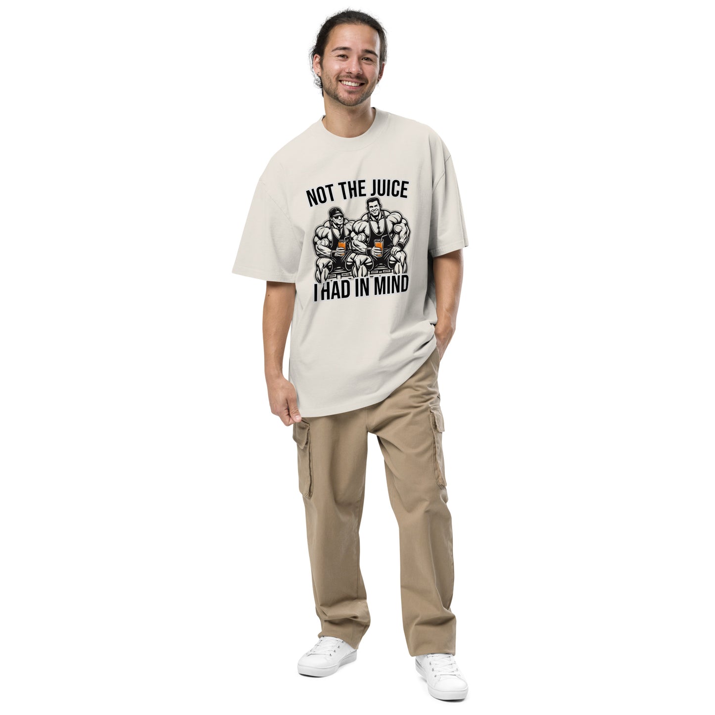 A smiling individual with long hair models Bougie Boiz Clubs Not The Juice - Oversized Faded T-shirt, featuring bodybuilders and the text Not the Juice I Had in Mind, paired with beige cargo pants and white sneakers, against a plain white backdrop.