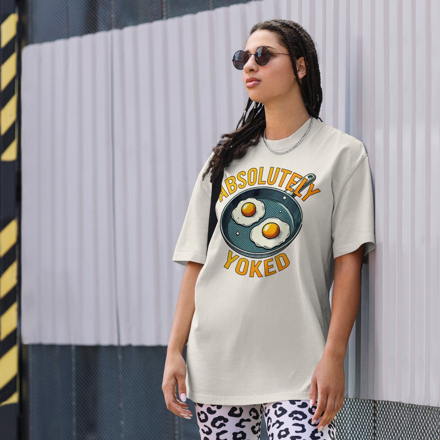 The Bougie Boiz Clubs Absolutely Yoked oversized faded dark gray T-shirt features a graphic of two sunny-side-up eggs in a pan, with bold yellow text above and below reading ABSOLUTELY YOKED, perfect for gym lifters.