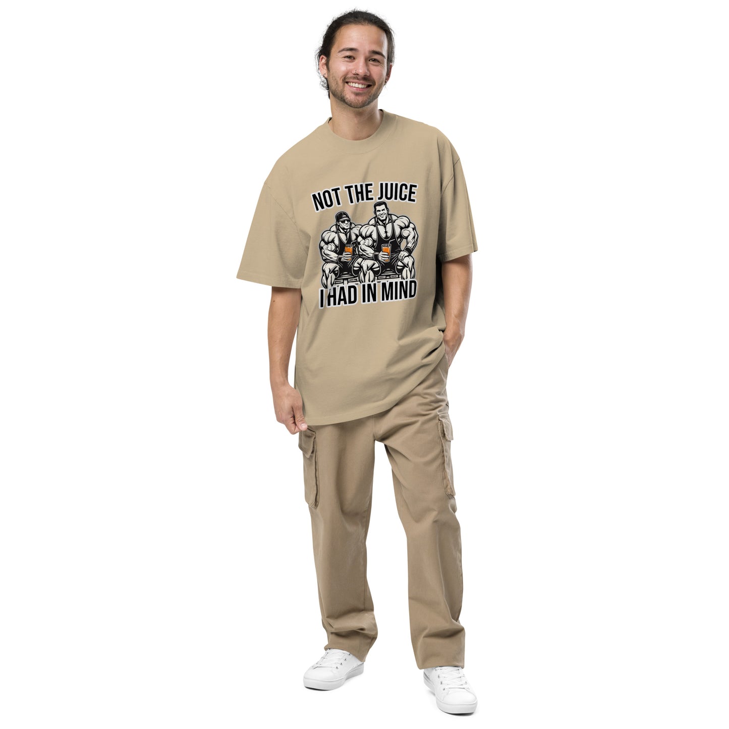 A smiling individual with long hair models Bougie Boiz Clubs Not The Juice - Oversized Faded T-shirt, featuring bodybuilders and the text Not the Juice I Had in Mind, paired with beige cargo pants and white sneakers, against a plain white backdrop.