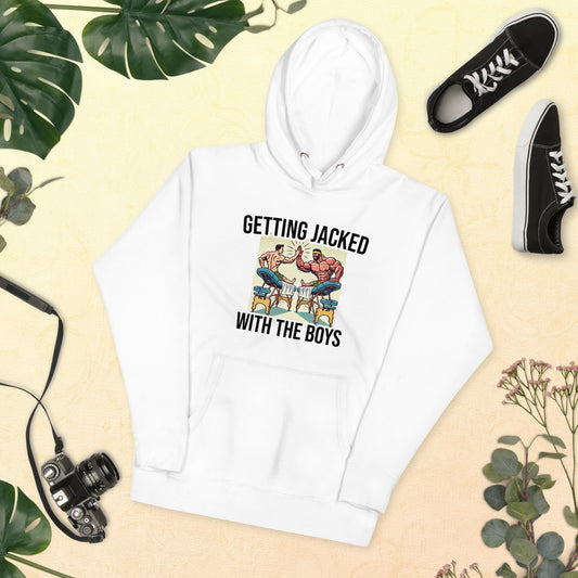 The Bougie Boiz Clubs Getting Jacked unisex white hoodie showcases a funny arm wrestling graphic with the text GETTING JACKED WITH THE BOYS. Surrounded by a camera, greenery, flowers, and sneakers on a textured backdrop, its ideal for gym buffs who enjoy humor.