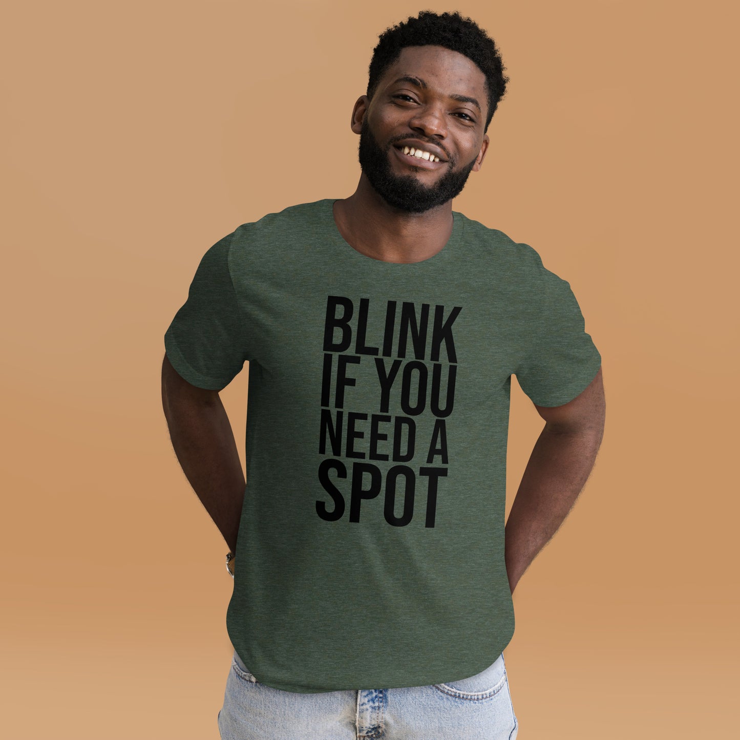 In the gym, a person wears the Bougie Boiz Club Blink If You Need A Spot Unisex T-shirt, highlighted amid weightlifting benches and exercise gear, perfectly setting off this quirky tee.