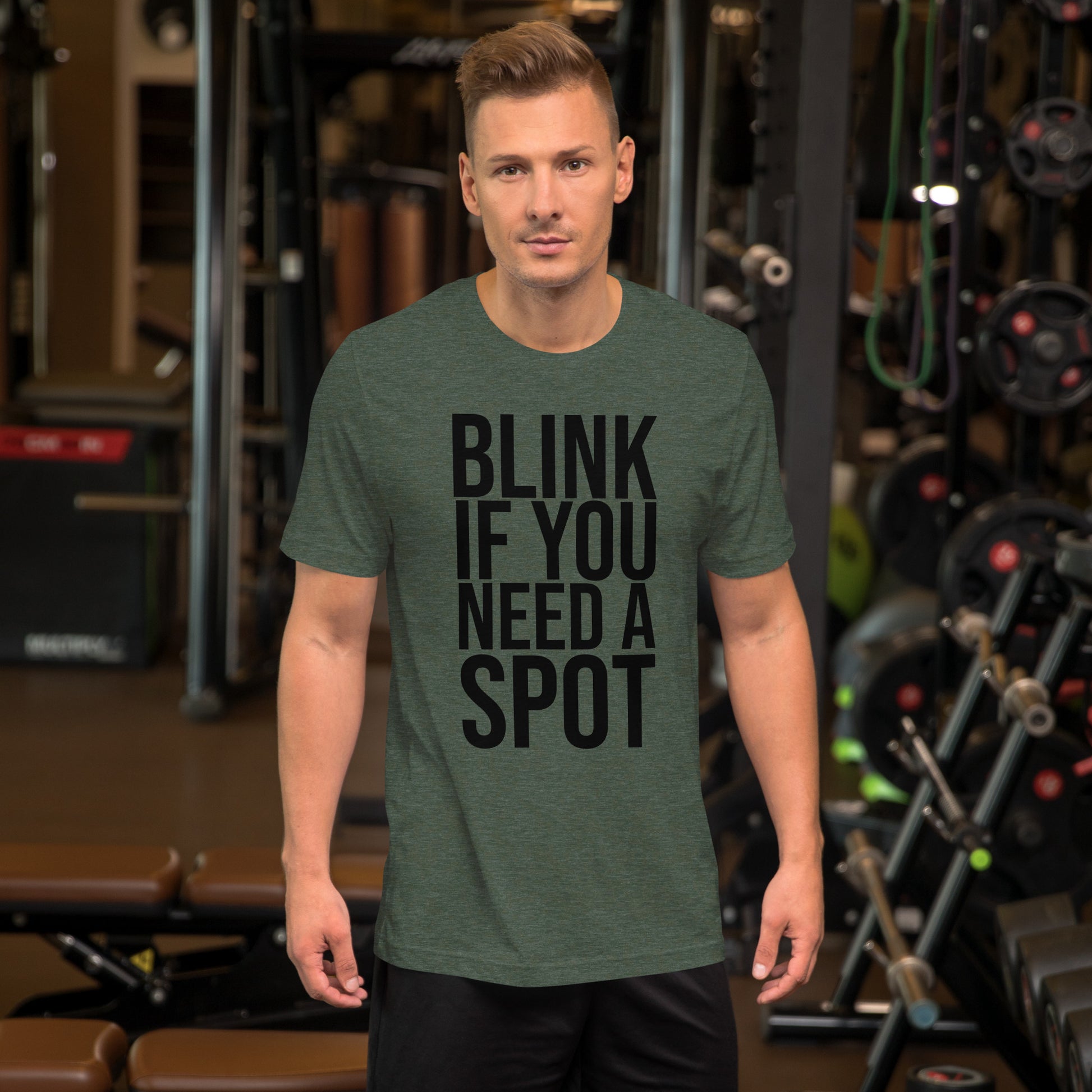 In the gym, a person wears the Bougie Boiz Club Blink If You Need A Spot Unisex T-shirt, highlighted amid weightlifting benches and exercise gear, perfectly setting off this quirky tee.