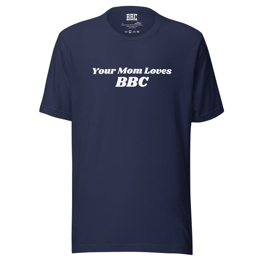 A smiling man combines humor and style in a navy Your Mom Loves BBC unisex T-shirt by Bougie Boiz Club, posing casually with hands in pockets against a neutral brown background. Ideal for gym or casual hangs, this look is both playful and relaxed.